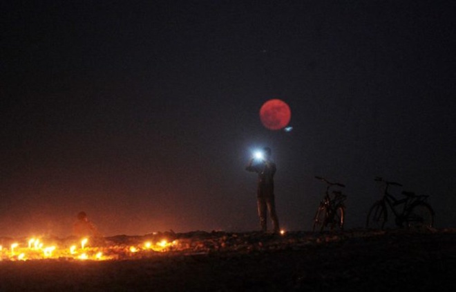 Một người đàn ông ghi lại khoảnh khắc chụp cùng siêu mặt trăng hôm 14/11/2016 tại Allahabad, Ấn Độ. Ảnh: Sanjay Kanojia. 