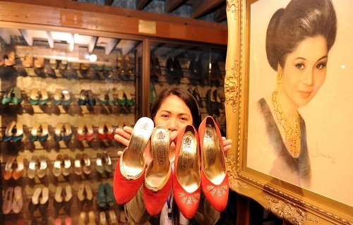 Một nhân viên bảo tàng cho khách xem một số đôi giày của vợ phó tổng thống Imelda Marcos, cạnh bức chân dung vẽ bà trong bảo tàng giày ở Manila. Ảnh: Ted Ajibe. 