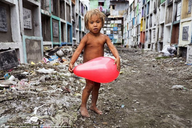 Một đứa trẻ sống trong khu ổ chuột tại Manila (Philippines) chơi đùa với quả bóng vừa nhặt được 