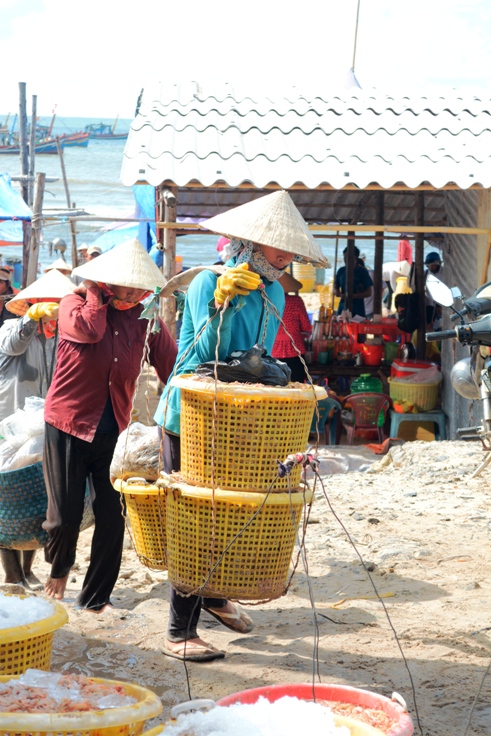 Ngư dân làng chài đang gánh cá lên bờ - Ảnh: Hồng Tâm 