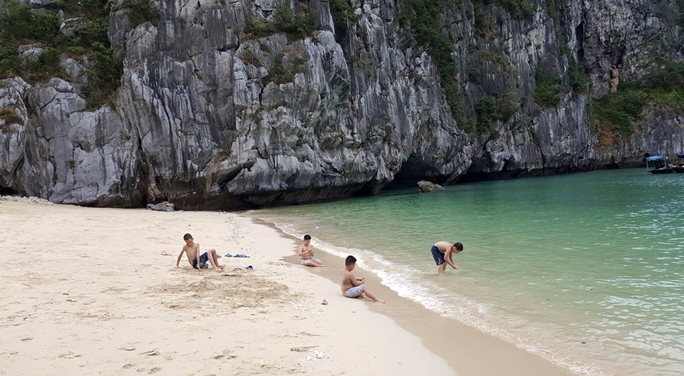 Trẻ em nô đùa nghịch cát và sóng ở đảo Mắt Rồng. 