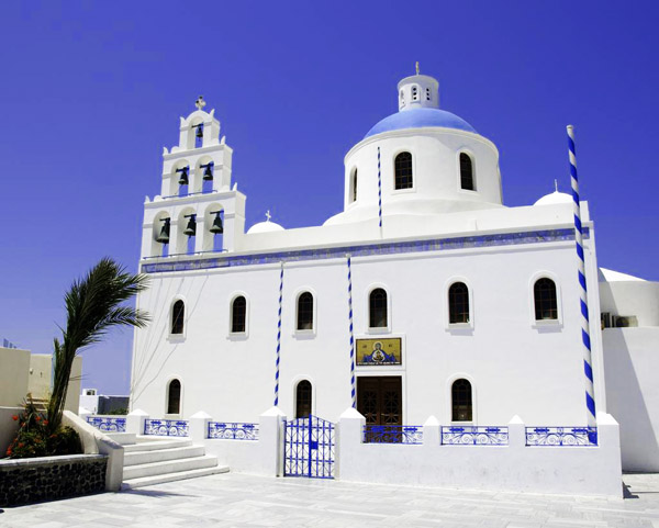Một ngôi chùa tại Oia Santorini với mái vòm màu xanh và tháp chuông màu trắng.