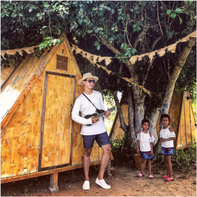 Hot traveler Nguyễn Thanh bên lều gỗ được đặt dưới tán cây lớn